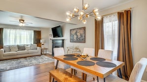 A modern living room with a wooden dining table, a sofa, and a television.