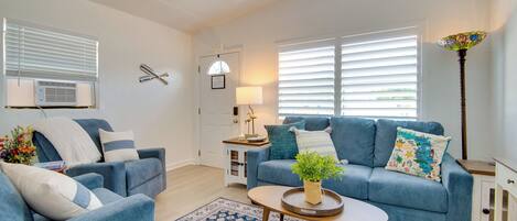 A living room with a blue sofa set, a coffee table with a plant, a patterned rug, and a lamp.