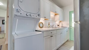 A modern kitchen with white cabinets, a built-in washing machine, a sink, and a green door.