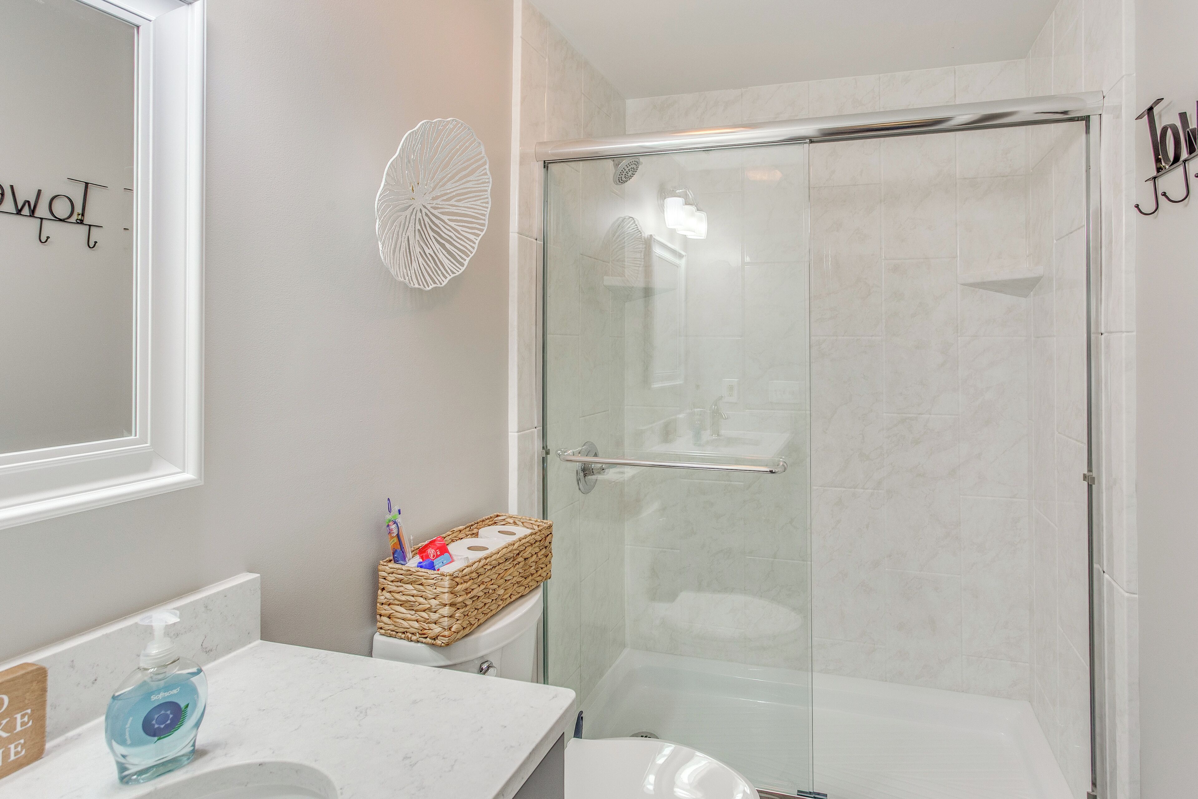 A modern bathroom with a glass shower enclosure, a white sink, and a decorative basket on the counter.