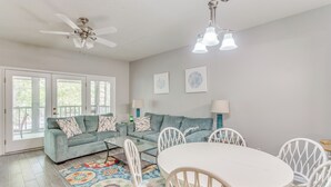 A living room with a sofa, a round table, and chairs. There is a ceiling fan, a chandelier, and a window with a view. - 3 Mi to Cherry Grove Beach: Coastal Condo Retreat! (North Myrtle Beach)
