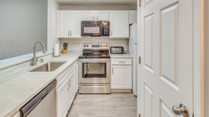 A modern kitchen with white cabinetry, stainless steel appliances, and a dishwasher. - 3 Mi to Cherry Grove Beach: Coastal Condo Retreat! (North Myrtle Beach)