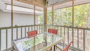A covered porch with a glass table and chairs, wooden railings, and a view of trees. - 3 Mi to Cherry Grove Beach: Coastal Condo Retreat! (North Myrtle Beach)