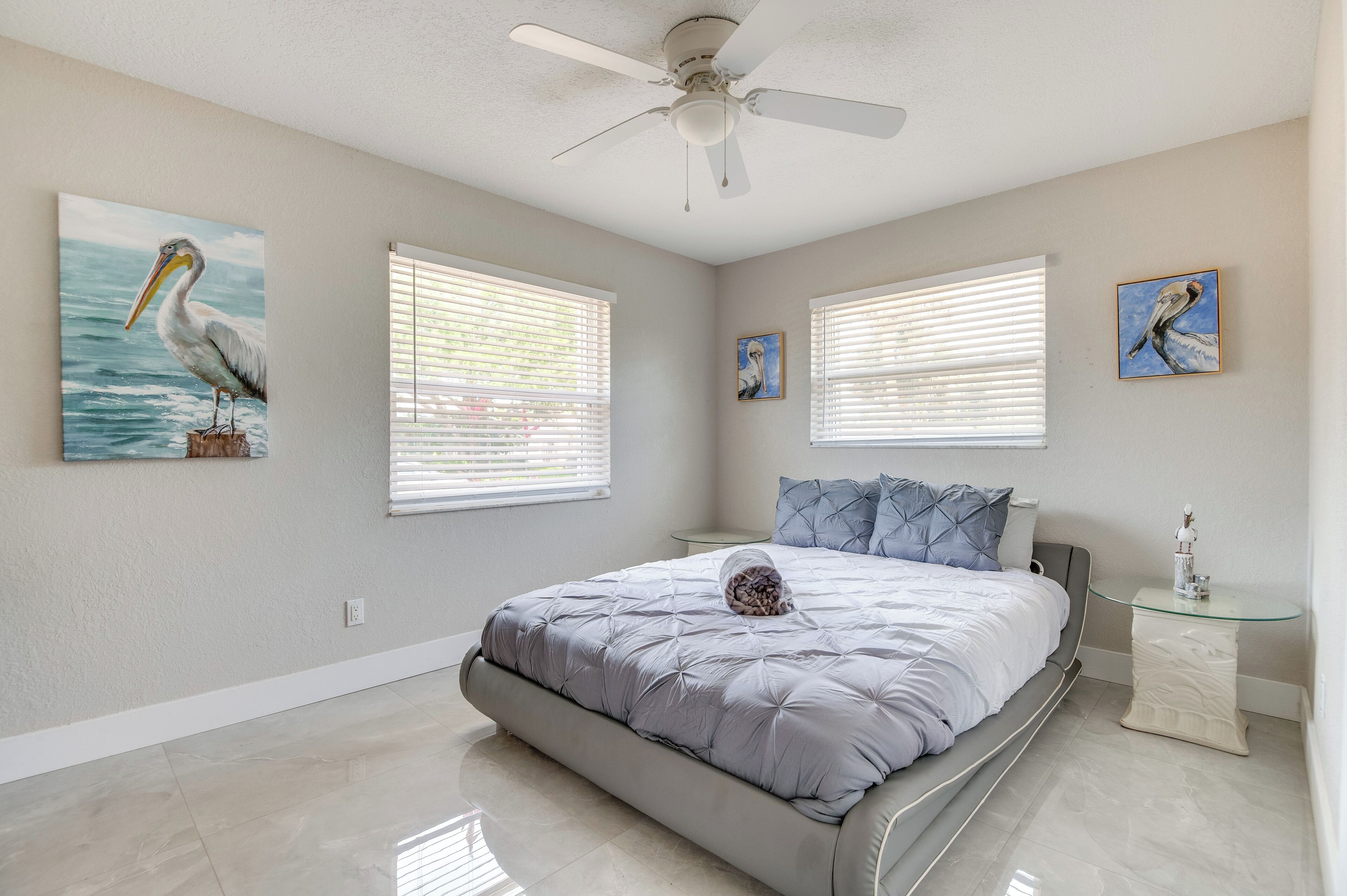 A bedroom with a bed, a ceiling fan, and artwork on the walls.