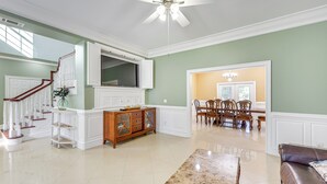 A spacious living room with a high ceiling, a dining area with wooden chairs, and a staircase with white railings. - 5 Mi to Beach: Spacious Home on Hilton Head Island (Hilton Head Island)