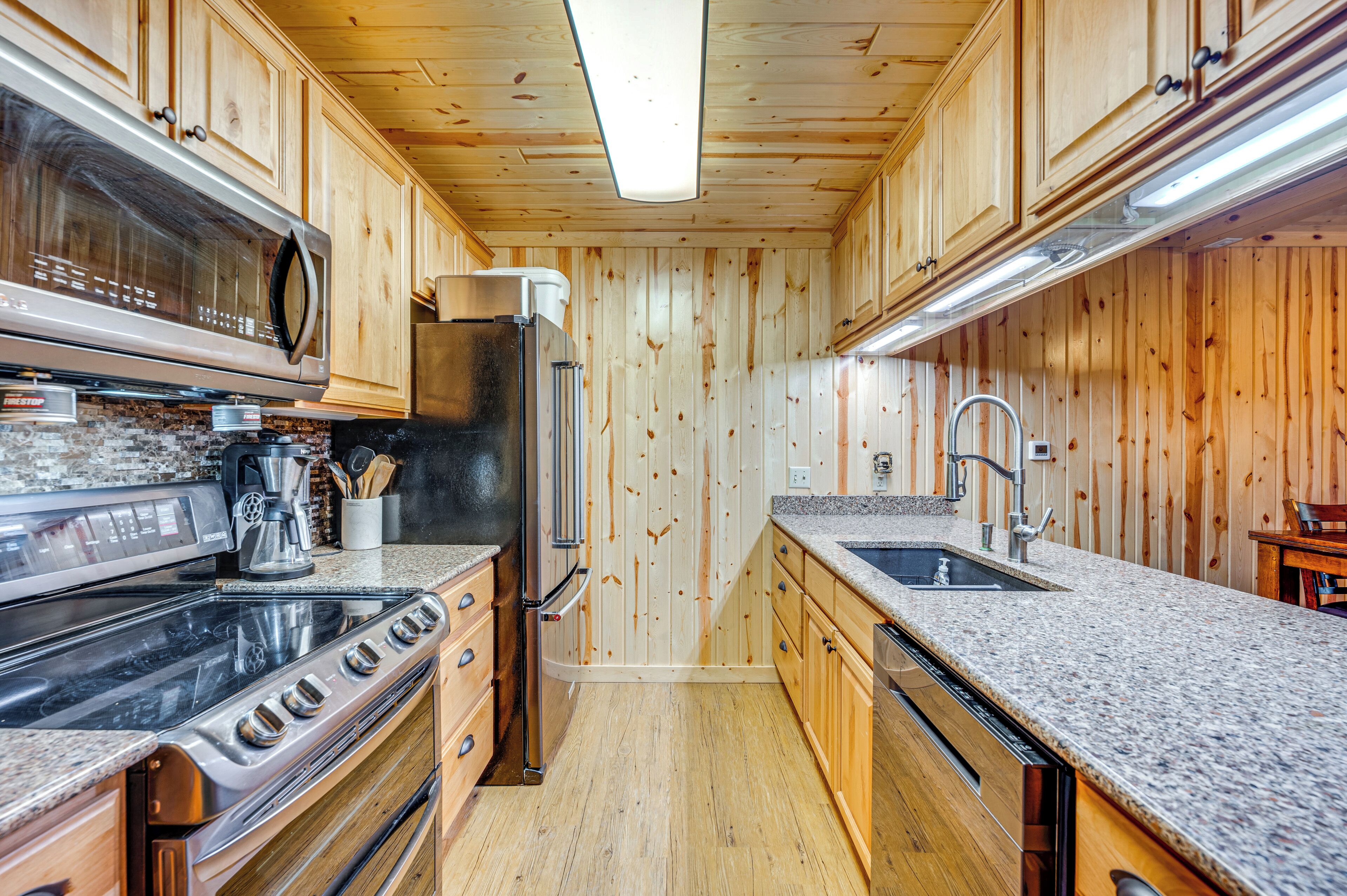 A compact kitchen with wooden cabinets, a stainless steel stove, and a granite countertop.