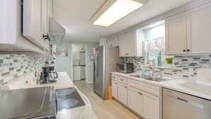 Une cuisine moderne avec des meubles blancs, un réfrigérateur en acier inoxydable, un four à micro-ondes et un lave-vaisselle.
