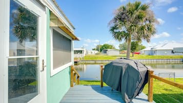 Enjoy outdoor dining or cooking on the covered grill, overlooking a serene body of water.