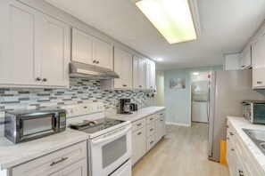 Une cuisine moderne avec des meubles blancs, un four à micro-ondes, une cuisinière et un réfrigérateur.