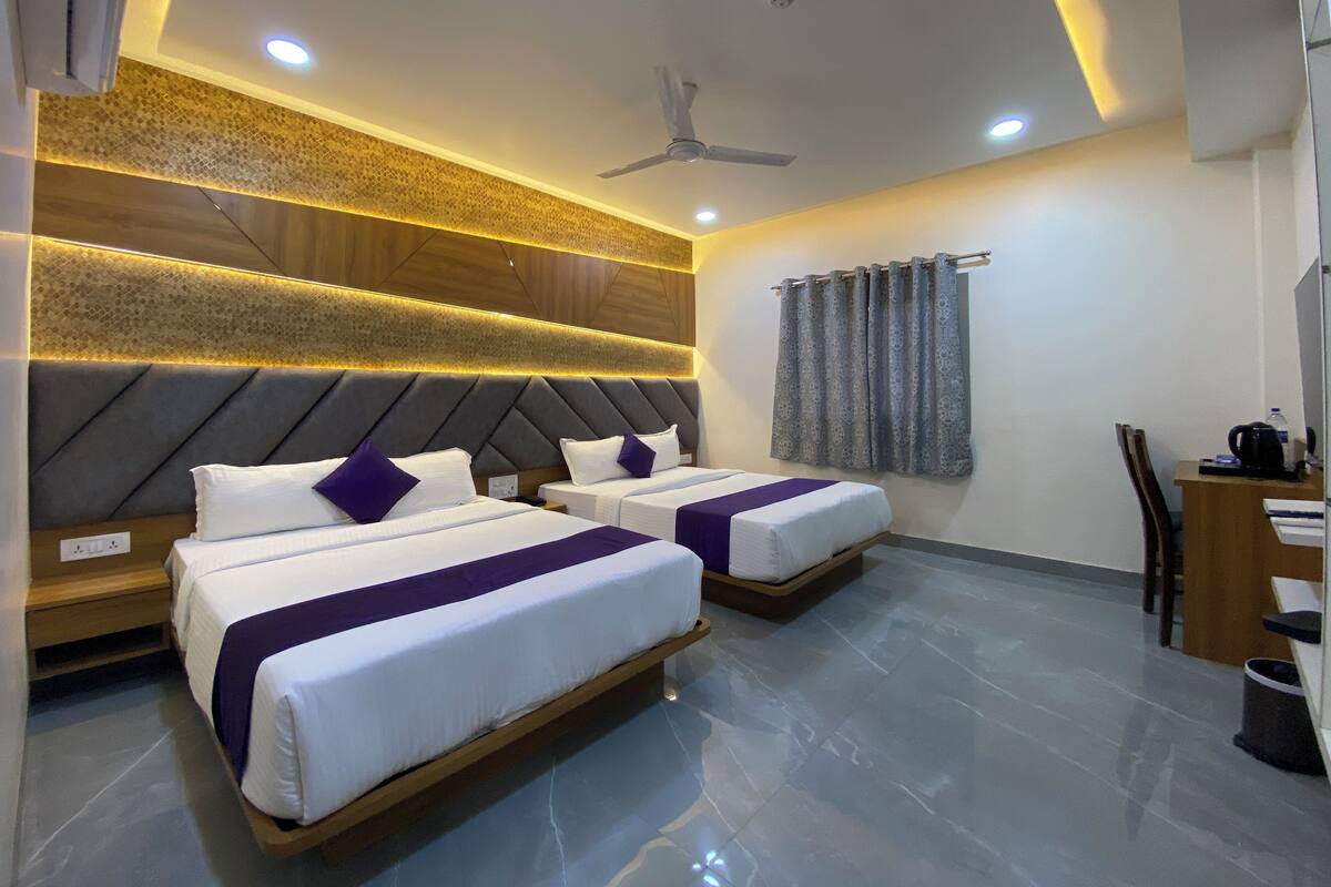 A hotel room with two beds, a desk, and a ceiling fan.