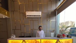 Un comptoir d’accueil avec un sol en marbre, un design moderne agrémenté de panneaux muraux géométriques et un appareil de climatisation installé au-dessus.