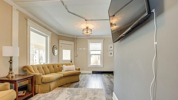 A living room with a sectional sofa, a lamp, and a flat-screen TV mounted on the wall. - Walk to Dtwn Green Lake: Peaceful Getaway w/ Porch (Green Lake)