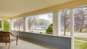 A covered porch with a wicker chair, large windows, and a view of a residential neighborhood. - Walk to Dtwn Green Lake: Peaceful Getaway w/ Porch (Green Lake)