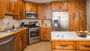 A kitchen with wooden cabinets, stainless steel appliances, and a countertop with a fruit bowl. - 1 Mi to Dtwn Black Mountain: Home w/ Patio & Yard (Black Mountain)