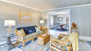 Een woonkamer met een bank, twee fauteuils, een salontafel, en een eethoek met een tafel en stoelen.