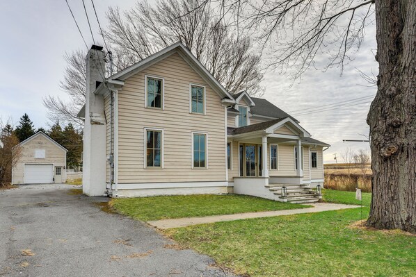 A two-story house with a front porch and a garage. - 3 Blocks to Lake Ontario: Getaway in Cape Vincent! (Cape Vincent)