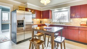 Een moderne keuken met roestvrijstalen apparatuur, houten krukken en rode keukenkastjes.
