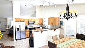 Une cuisine spacieuse avec des meubles en bois, un îlot central et un lustre.