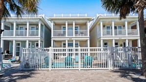 Une propriété située en bord de mer, dotée d’une piscine, de plusieurs balcons et d’une clôture blanche.