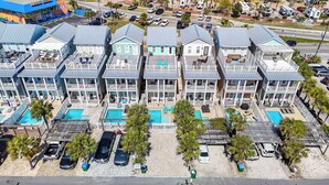 Une rangée de bungalows situés en bord de mer, dotés de plusieurs balcons, d’une piscine et d’un espace de stationnement.