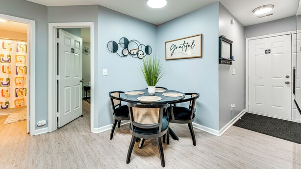 A dining area with a round table, four chairs, a potted plant, and a framed quote on the wall. - Near Speedway & Shops: Concord Apt w/ Shared Yard! (Concord)