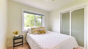 A bedroom with a bed, a nightstand, a window, and a sliding door.
