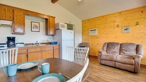 Una cocina acogedora con armarios de madera, un refrigerador blanco y una mesa de comedor con platos y tazas.