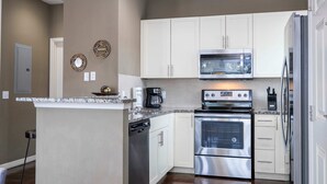 Une cuisine moderne avec des meubles blancs, des appareils en acier inoxydable, un four encastré et un four à micro-ondes.