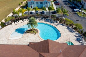 A swimming pool with a curved design, surrounded by lounge chairs and a palm tree. - Spacious 4Bd Disney Dream With Resort Access at Lucaya 3210 (Kissimmee)