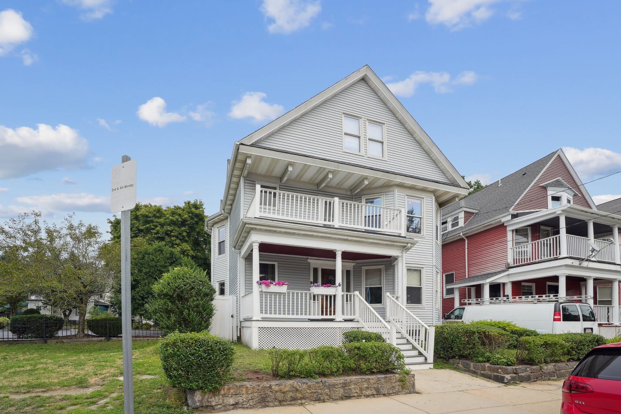 Une maison à deux étages avec un balcon, une véranda et une allée.