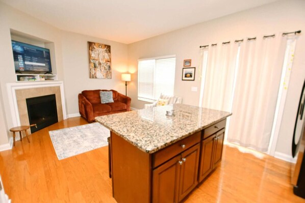 A kitchen with a granite countertop, wooden cabinets, a fireplace, a sofa, and a dining area.