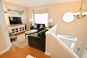 A living room with a flat-screen TV, a sofa, a coffee table, and a staircase leading to an upper level. - Spacious 3br 3. 5 bath townhome w/garage (123p) (South Bend)