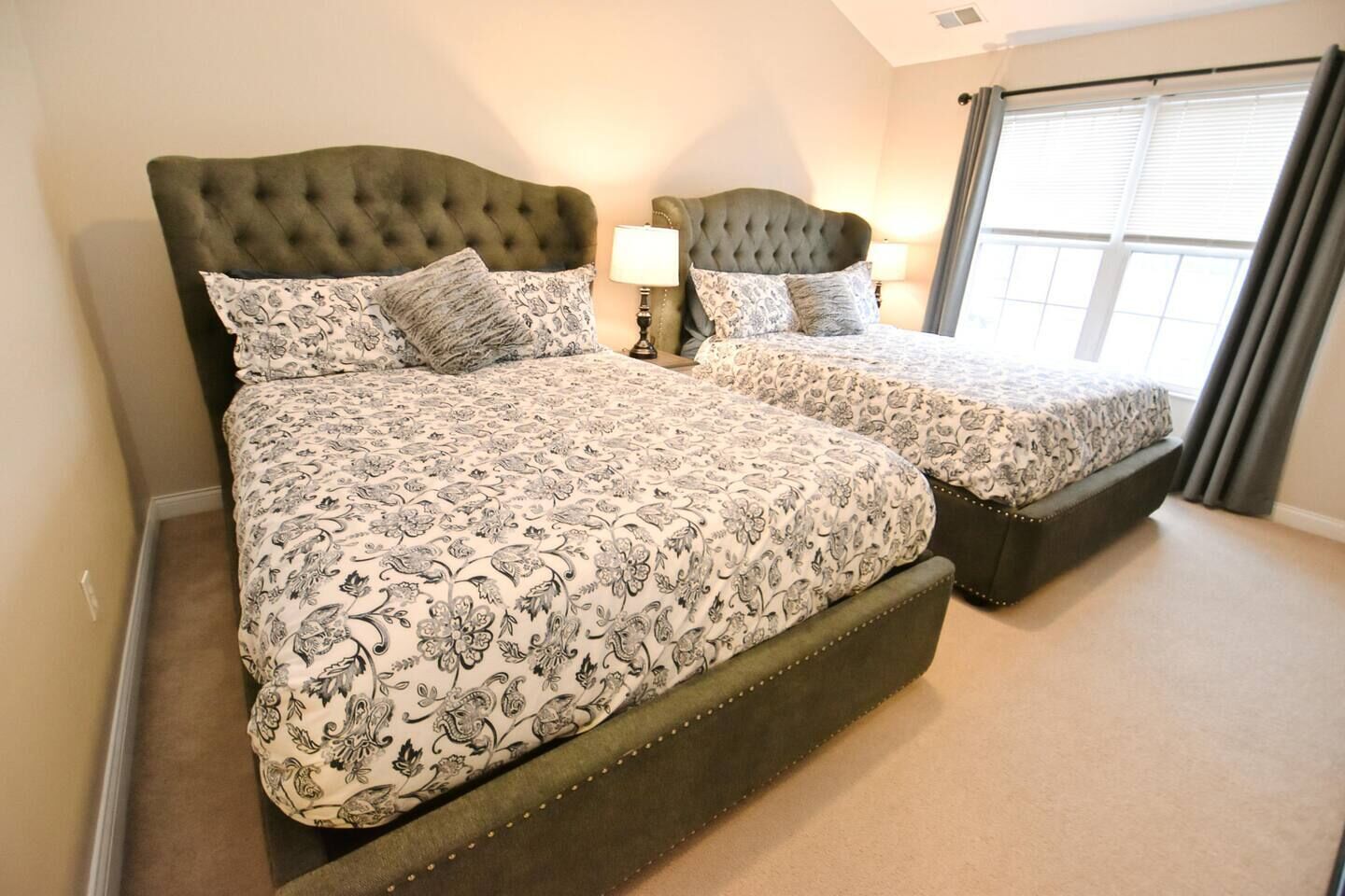 A double bed with a tufted headboard and a matching footboard, flanked by two bedside tables with lamps.
