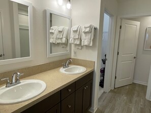 A bathroom with two sinks, a mirror, and a towel rack.