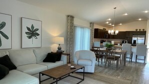Ein modernes Wohnzimmer mit Sofa, Couchtisch und einem Essbereich mit Stühlen und einem Tisch.