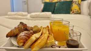 A breakfast tray with croissants, bread, and juice on a bed with pillows and a headboard. - Happy Family Apartments Soziglia (Genoa)