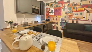 A modern kitchen with a dining area, a black stove, a microwave, and a sink. - Happy Family Apartments Soziglia (Genoa)