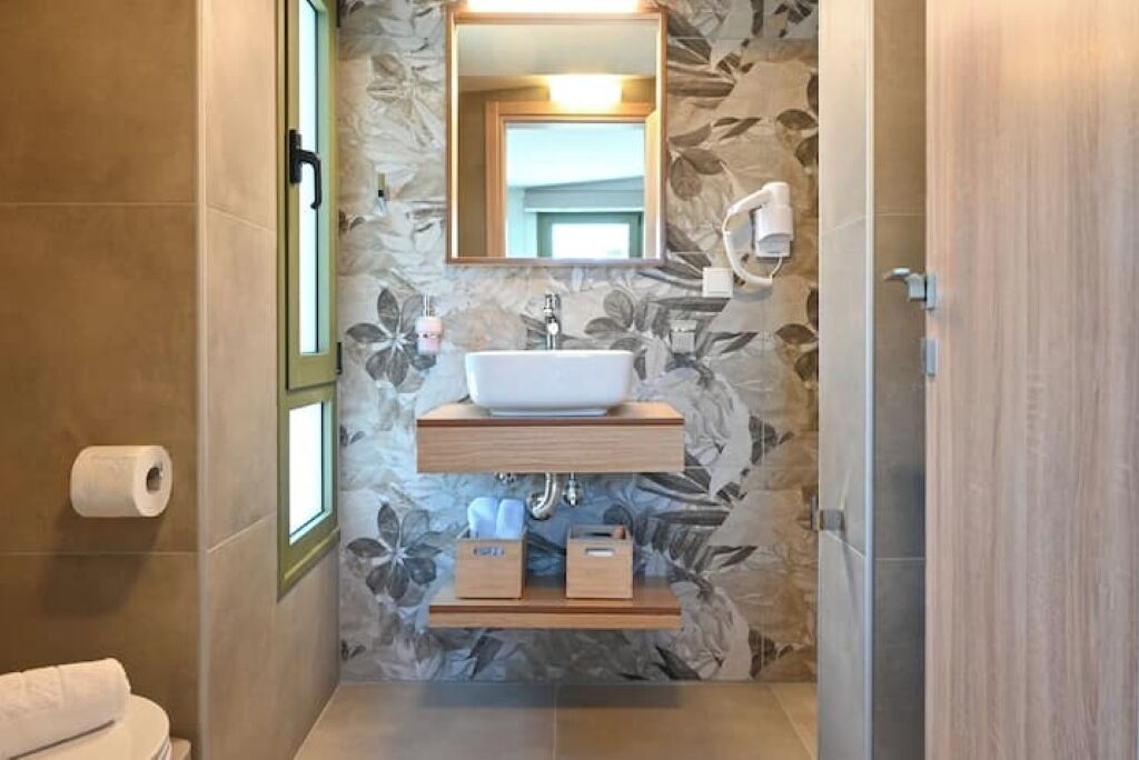 Een badkamer met een houten wastafel, een witte wasbak, een spiegel en een douchehoek.