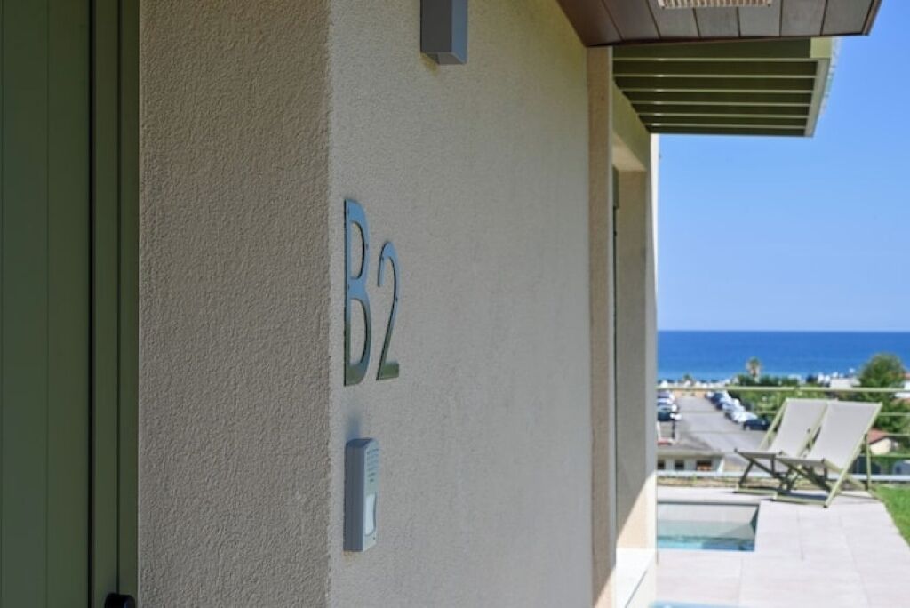 En bygning med balkon, pool og havudsigt.