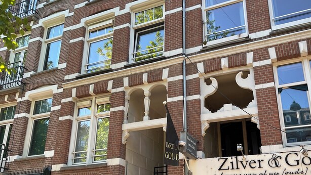 A multi-story building with a brick facade, large windows, and a visible entrance with a staircase.
