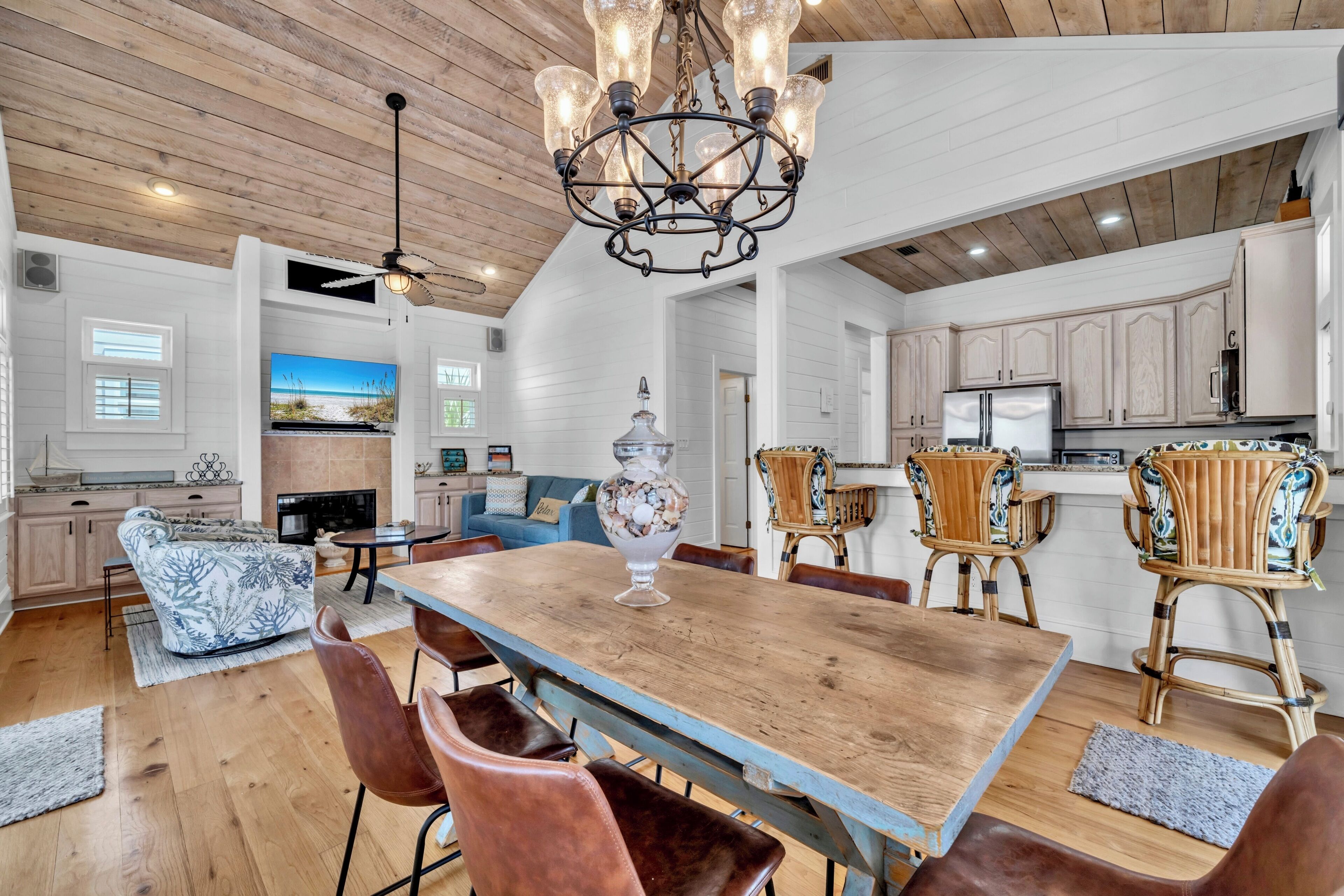 A spacious kitchen with wooden cabinets, a dining area with a wooden table and chairs, and a chandelier.