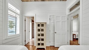 Ein Schlafzimmer mit zwei Betten, einem weißen Kleiderschrank und einer Tür zu einem anderen Raum.