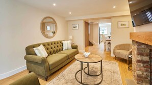 A living room with a green sofa, a round coffee table, and a fireplace. - Host & Stay | Ginger Bread Cottage (Stokesley)