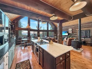 A spacious kitchen with a large island, wooden flooring, and a view of the outdoors.