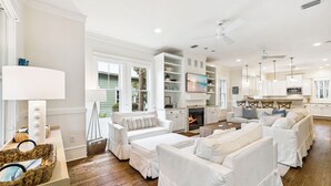 A spacious living room with white furniture, a fireplace, and a kitchen area. - Private Pool and LSV Watercolor Getaway (Santa Rosa Beach)