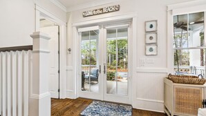 A clean, white interior with a wooden floor, a blue patterned rug, and a 'GONE to the BEACH' sign above a glass door leading to an outdoor patio. - Private Pool and LSV Watercolor Getaway (Santa Rosa Beach)