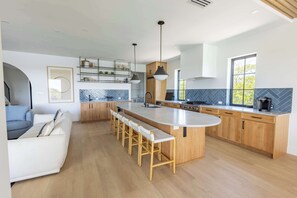 A modern kitchen with a central island, wooden cabinets, and a built-in oven. - The Starboard House at Solaire Lunara Bay (Key West)