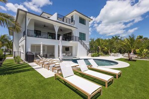 A two-story house with a swimming pool, outdoor seating, and a covered patio area. - The Starboard House at Solaire Lunara Bay (Key West)