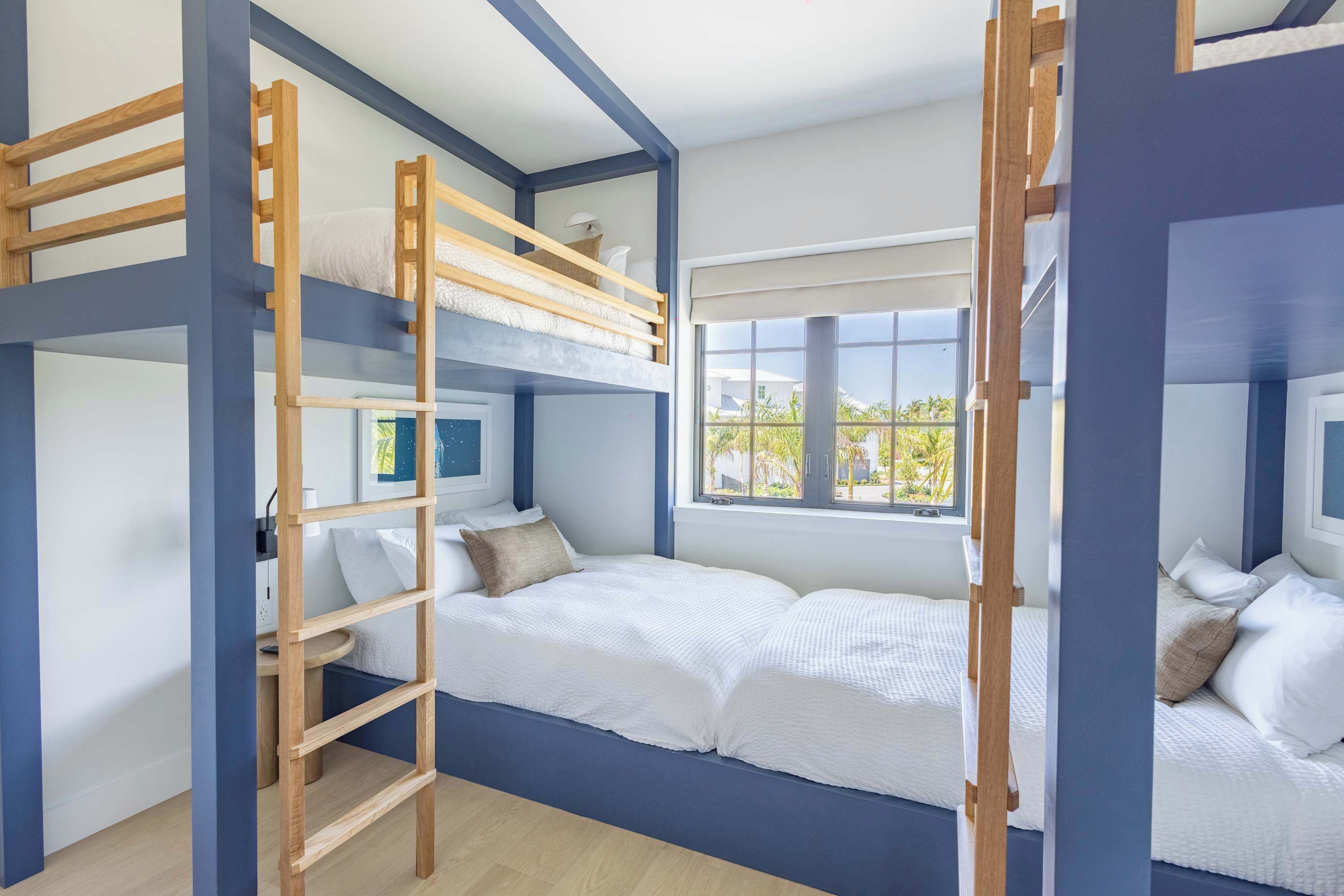 Een slaapkamer met stapelbed, een ladder, een raam met uitzicht en een nachtkastje.