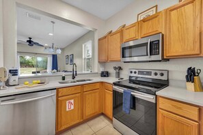 A modern kitchen with wooden cabinets, stainless steel appliances, and a window overlooking a garden. - Peaceful Townhome w/ Patio & Resort Access (Davenport)